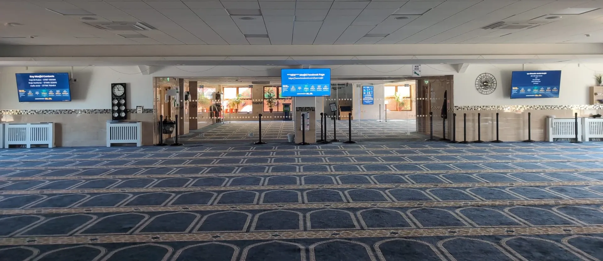The main prayer hall at Lye Ghausia Jamia Masjid, with MasjidConnect screens on the far wall